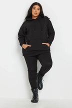 Siyah kapüşonlu büyük beden sweatshirt ve pantolon giymiş kadın, rahat ve modern kombin