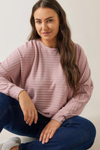 Pudra renkli, çizgili büyük beden sweatshirt ve kot pantolon giyen kadın