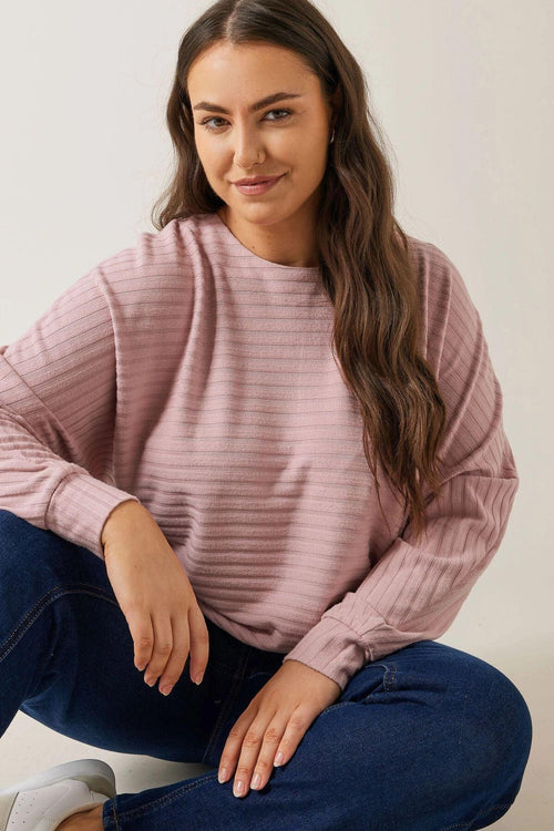 Pudra renkli, çizgili büyük beden sweatshirt ve kot pantolon giyen kadın
